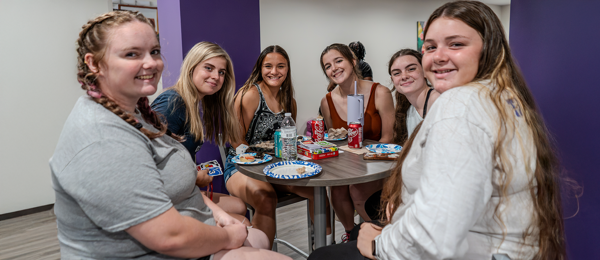 6 Students smiling while sitting around a table