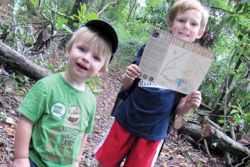 Two boys hiking in the arboretum holding up the map