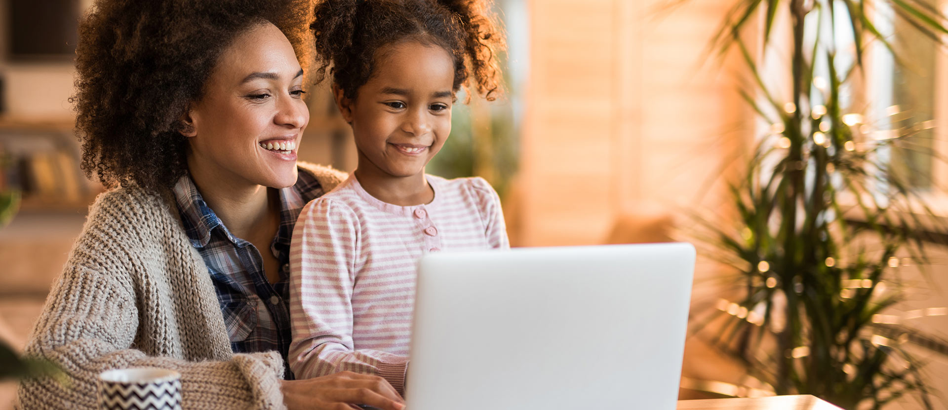 Mother and daughter sit and look at the laptop.